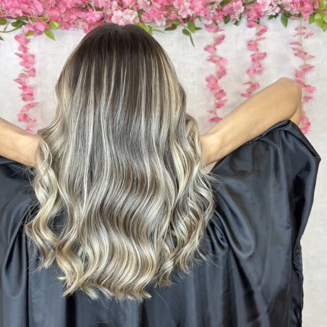 Blond gris-sable en longues ondulations devant un fond de fleurs roses