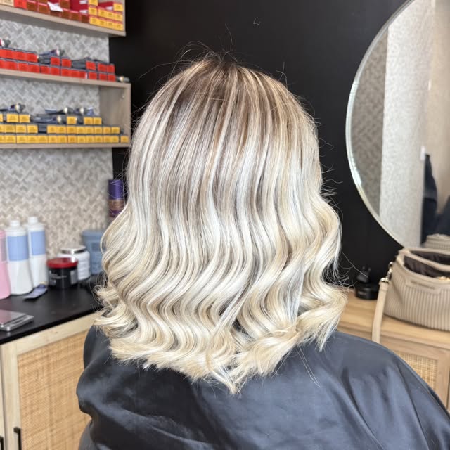 Carré blond platine ondulé devant le miroir rond du salon